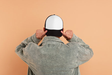 Man in stylish baseball cap on beige background, back view. Mockup for designの写真素材