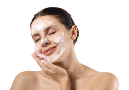 Beautiful woman washing her face with cleansing foam on white backgroundの写真素材