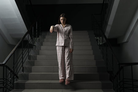 Woman suffering from sleepwalking on stairs indoorsの写真素材