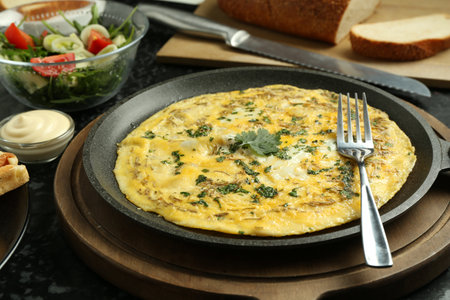 Tasty brunch. Delicious omelette and salad served on black textured table, closeupの写真素材