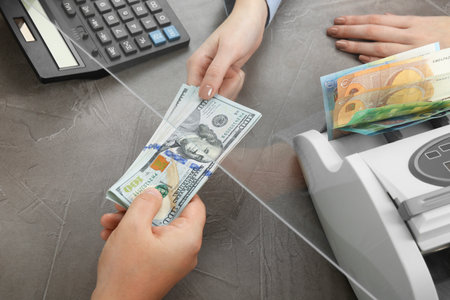 Cashier giving dollar banknotes to client at table in money exchange, closeupの写真素材