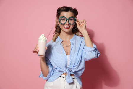 Happy pin-up woman with milk shake on pink backgroundの写真素材