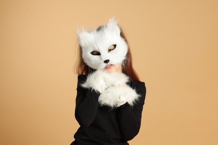 Quadrobics. Girl wearing cat mask and gloves on beige backgroundの写真素材
