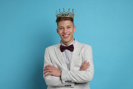 Handsome man wearing luxury crown on light blue backgroundの写真素材