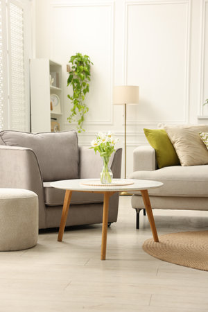 Stylish furniture and houseplants in light living room. Interior design