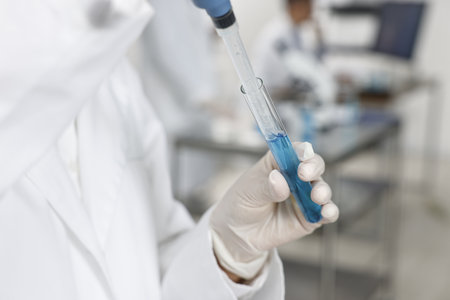 Scientist with micropipette and test tube working in laboratory, closeup
