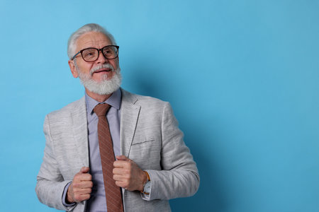 Portrait of senior man with gray beard on light blue background. Space for text