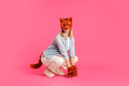 Quadrobics. Woman wearing fox mask, gloves and tail on pink backgroundの写真素材