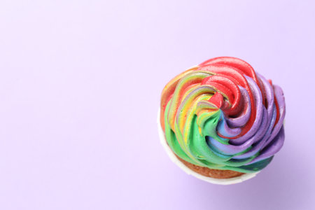 Delicious cupcake with colorful cream on violet background, top view. Space for textの写真素材