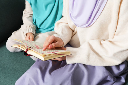 Muslim woman and her daughter reading Quran at home, closeupの写真素材