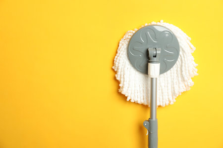 String mop on yellow background, top view. Space for text