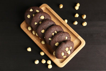 Delicious chocolate cookies with hazelnuts on black wooden table, flat layの写真素材