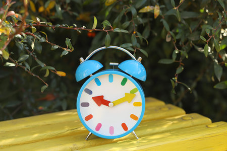 Alarm clock on bench outdoors, closeup