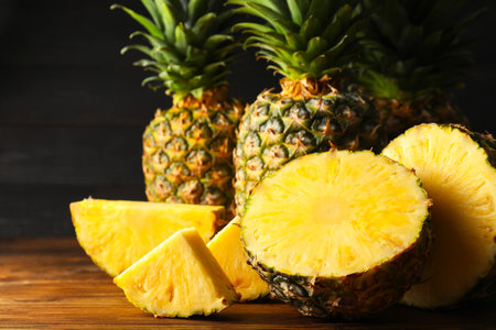 Whole and cut ripe pineapples on wooden table