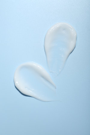Cream samples on light blue background, top view