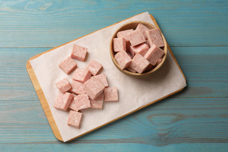 Pieces of canned meat on blue wooden table, top view