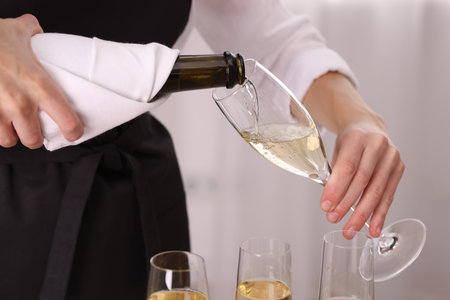Waiter pouring champagne into glass indoors, closeupの写真素材