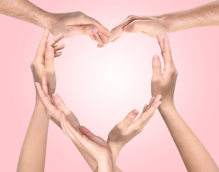 People making heart shape with hands on pink background. Teamwork, unity, togethernessの写真素材