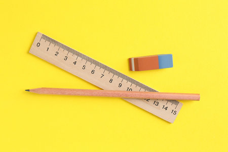 Ruler, pencil and eraser on yellow background, flat layの写真素材