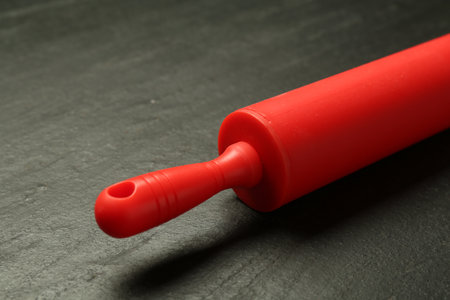 Red rolling pin on dark gray textured table, closeupの写真素材