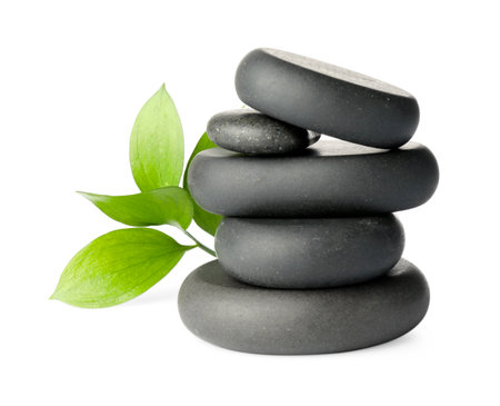 Stacked spa stones and green leaves isolated on whiteの写真素材