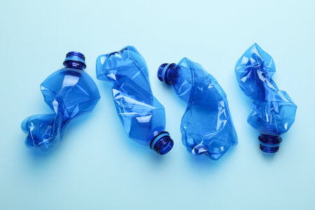 Crumpled plastic bottles on light blue background, flat layの写真素材