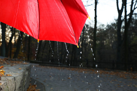 Open red umbrella under pouring rain outdoors, closeup. Space for textの写真素材