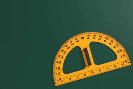Protractor ruler on green chalkboard, top view. Space for text