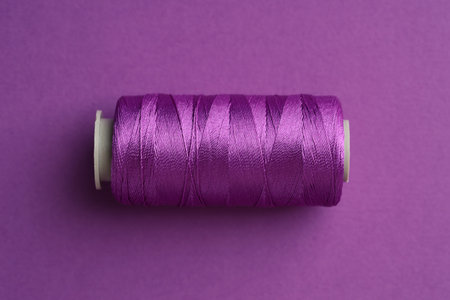 Spool of sewing thread on violet background, top viewの写真素材