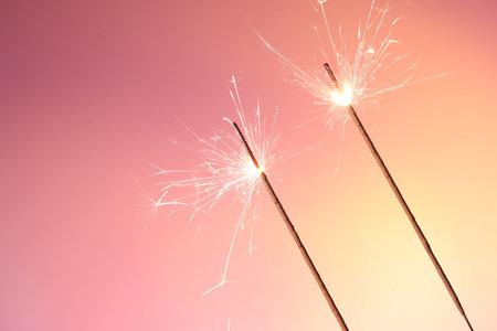 Bright burning sparklers on color gradient background, closeup. Space for text
