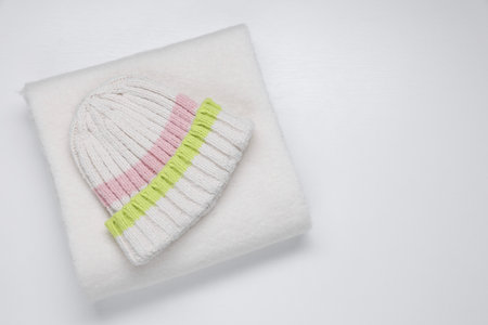 Stylish knitted hat and warm scarf on white background, top view.