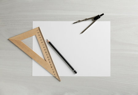 Paper, ruler, compass and pencil on white wooden table, flat lay. Space for text
