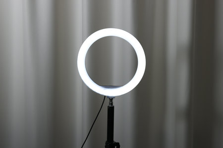 One glowing ring lamp near grey curtain