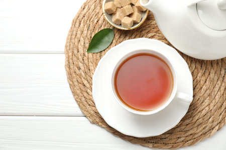 Aromatic black tea and brown sugar cubes on white wicker table, top view. Space for textの写真素材
