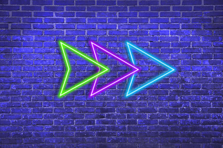 Bright neon arrow-shaped pointer on blue brick wall