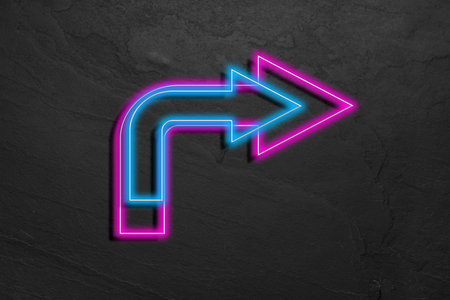 Bright neon arrow-shaped pointer on gray textured wall