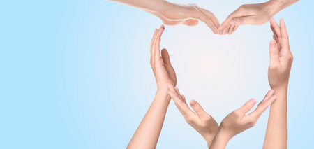 Heart shape made with hands of different people on light blue background, banner design with space...
