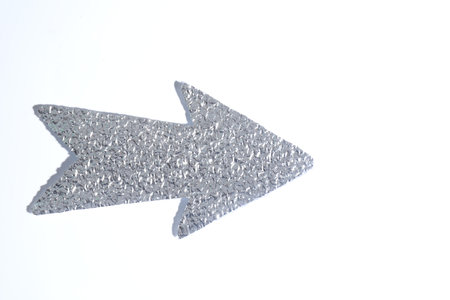 Silver tinfoil arrow on white background, top view. Space for textの写真素材