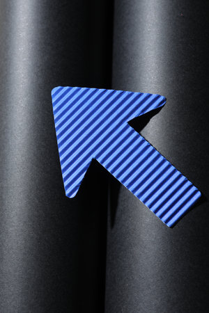 One blue paper arrow on black background, top viewの写真素材