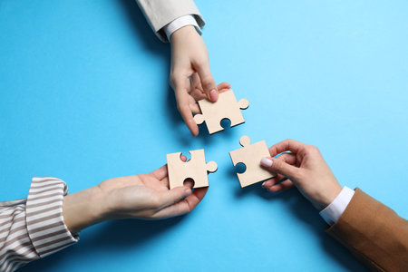 Business strategy and teamwork concept. Partners with different puzzle pieces on light blue...