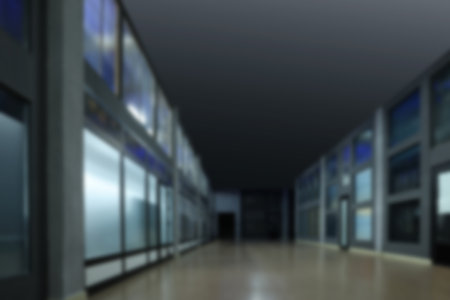 Blurred view of empty office corridor with glass walls