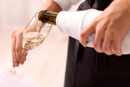 Waiter pouring champagne into glass indoors, closeupの写真素材