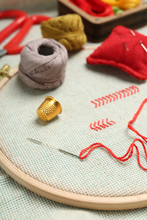 Embroidery. Canvas with cross stitches and supplies on table, closeup