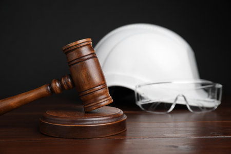 Accident at work concept. Gavel and construction worker's protective gear on wooden table, selective focusの写真素材