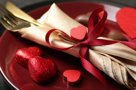 Romantic place setting for Valentine's day. Tableware, cutlery and candies in shape of hearts on table, closeupの写真素材