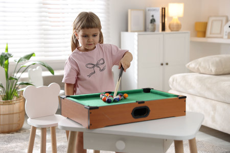 Cute little girl playing billiards at home
