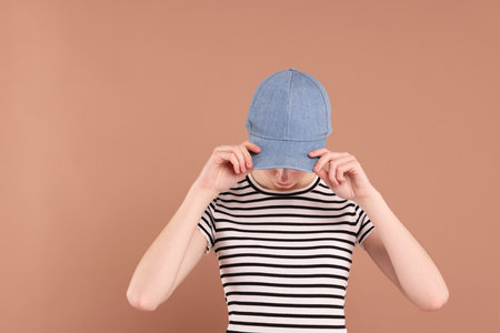 Woman in stylish baseball cap on beige background. Mockup for designの写真素材