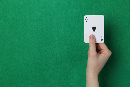 Woman with playing card against green background, closeup.