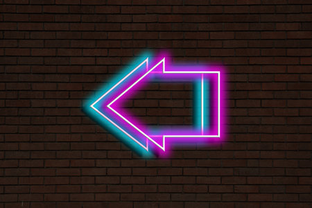 Bright neon arrow-shaped pointer on brick wallの写真素材