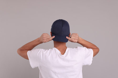 Man in stylish baseball cap on grey background, back view. Mockup for designの写真素材